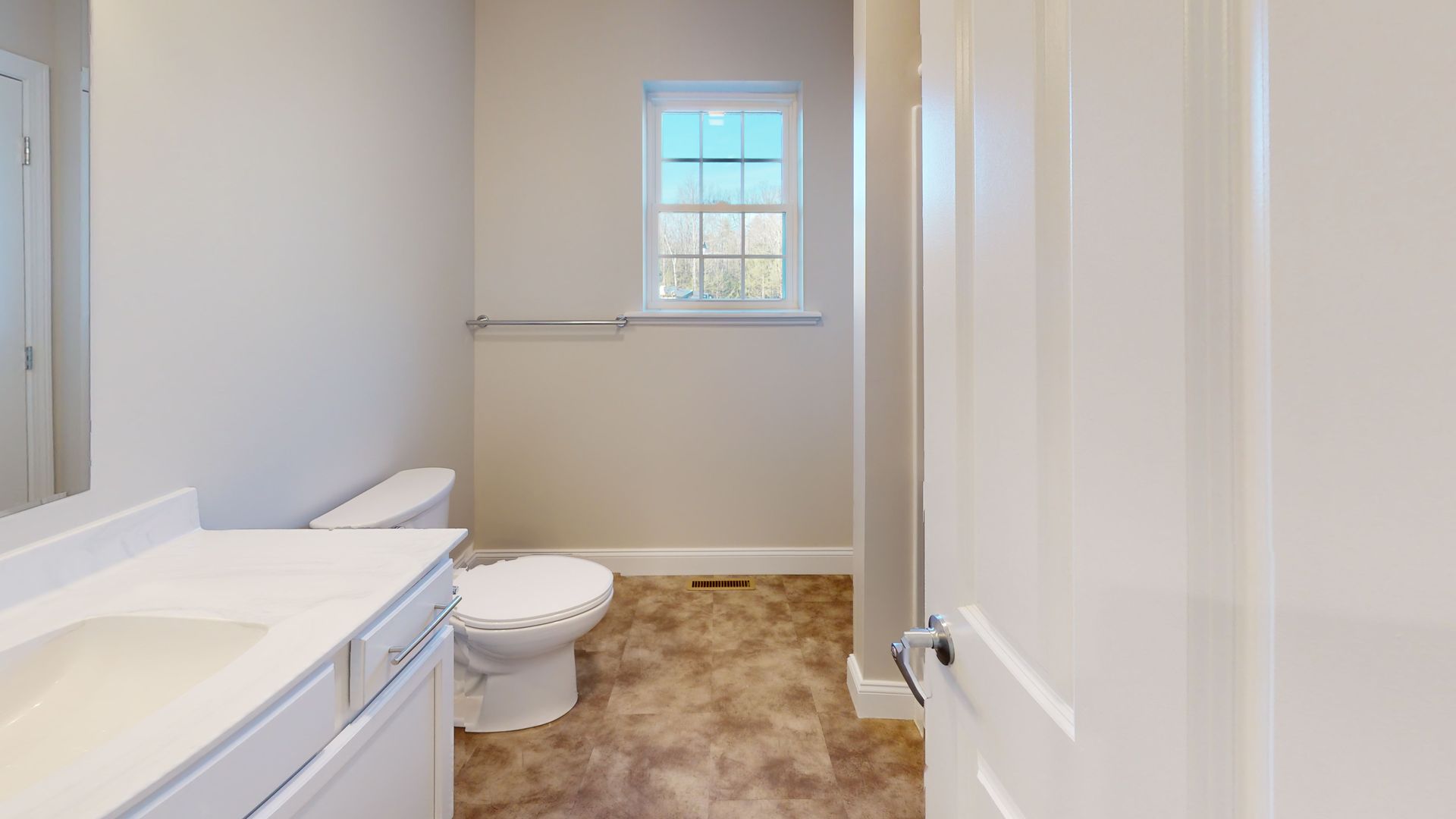 A bathroom with a toilet , sink , mirror and window.
