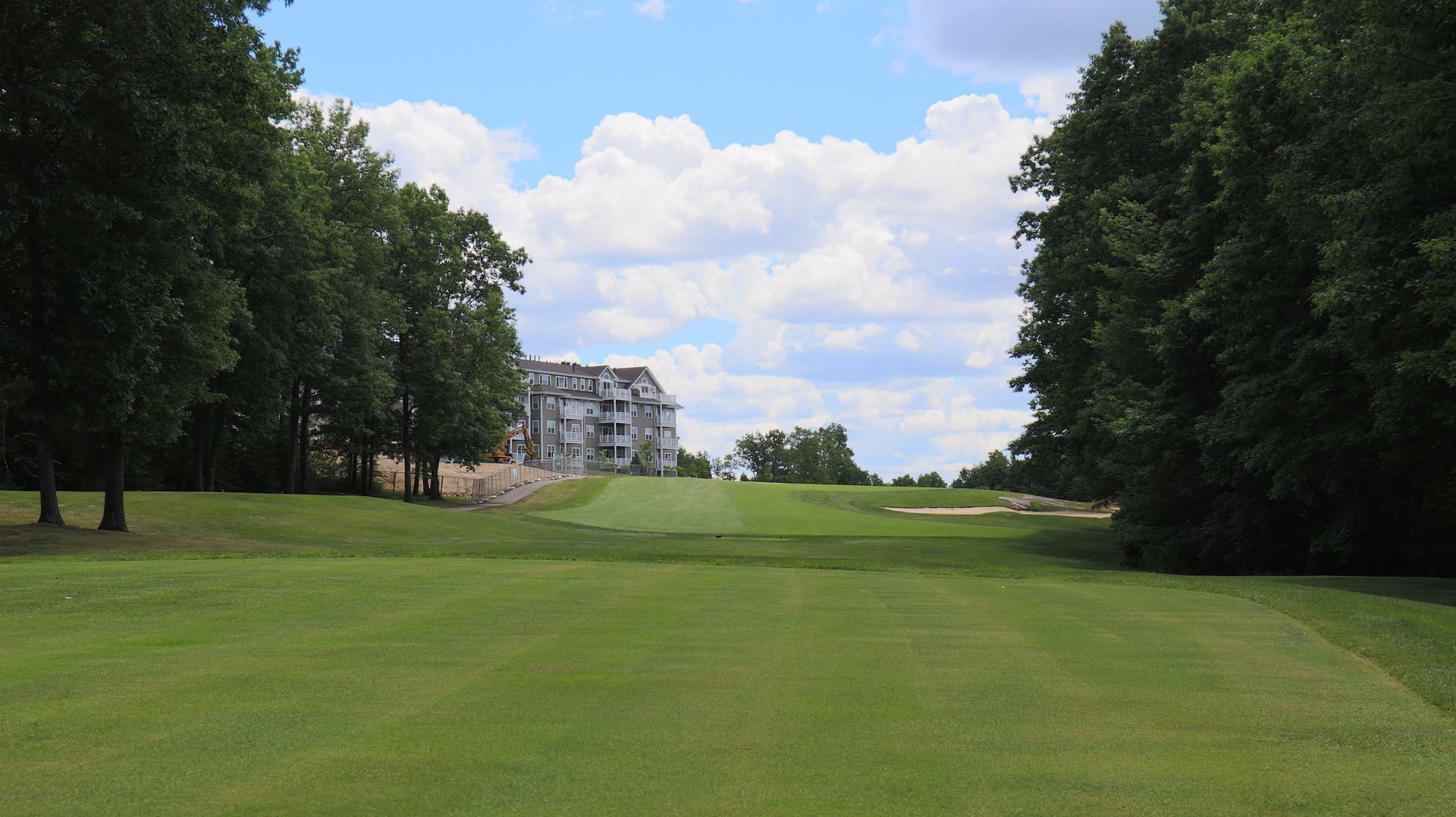 A golf course with trees and a building in the background