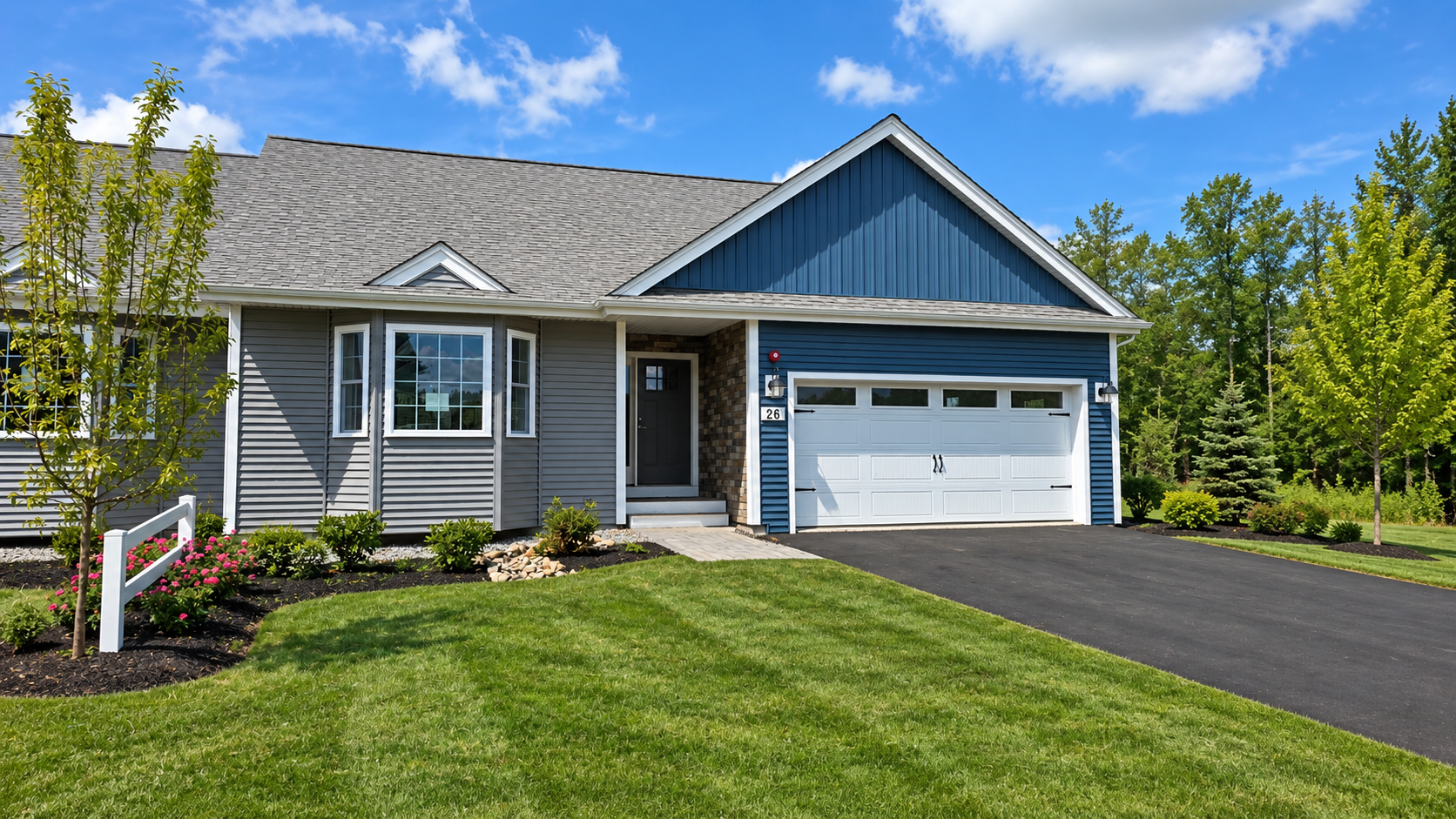 Suburban gray house with blue gable, white garage, black driveway, and neatly trimmed green lawn