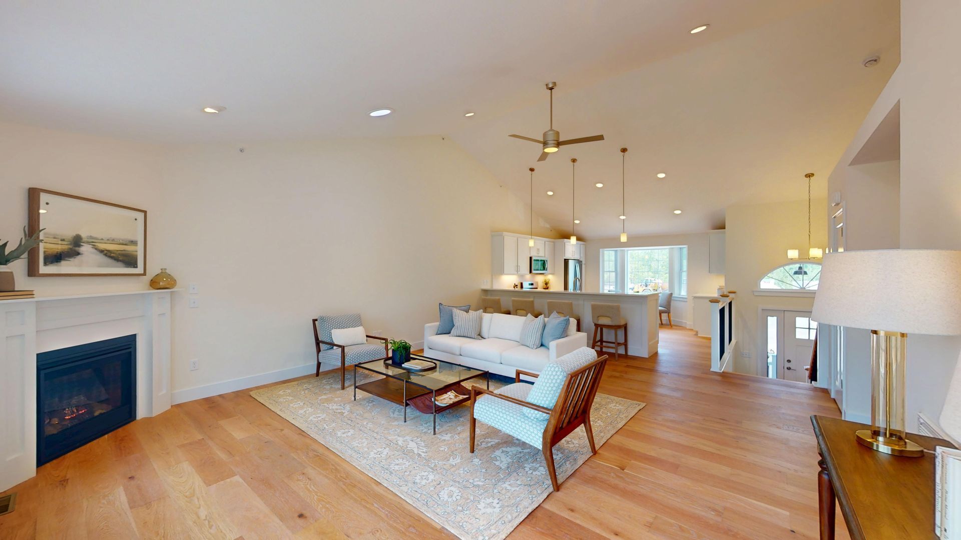 Bright living room with wood floors, white sofas, blue fireplace, and dining area beyond