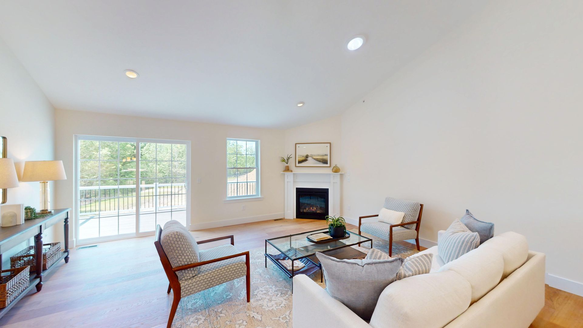Bright living room with white walls, fireplace, sofa, chairs, and sliding glass doors to a patio