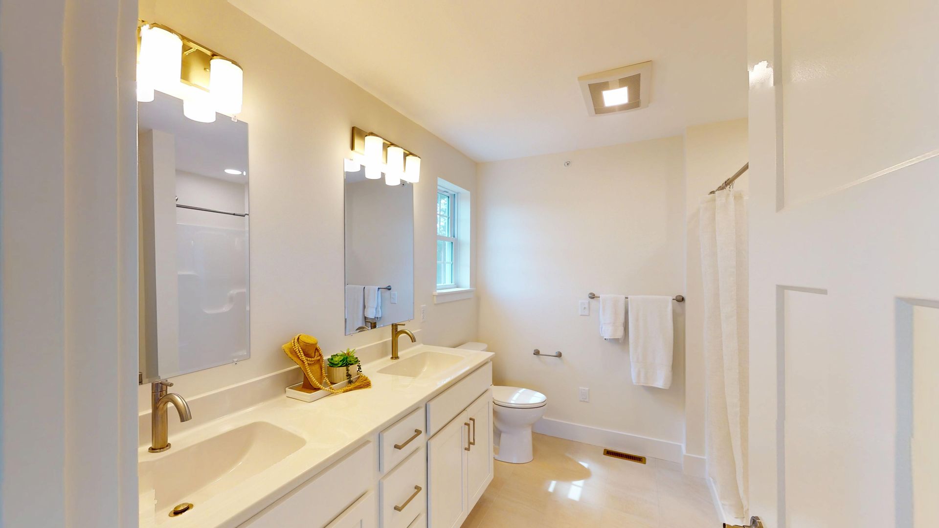 A bathroom with two sinks , a toilet and two mirrors.