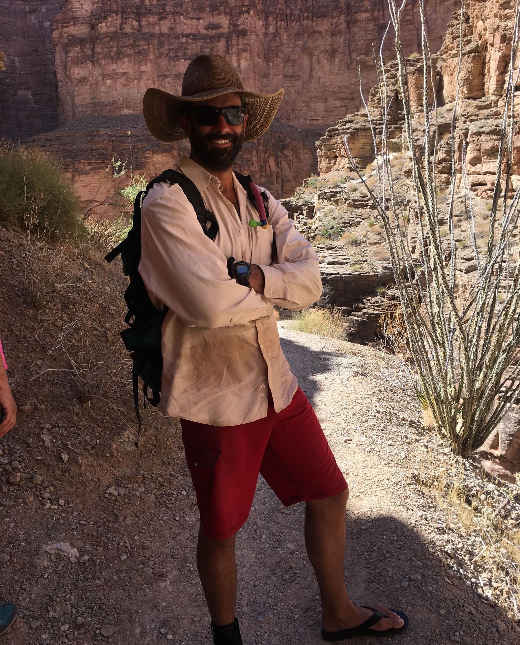 A man with a beard is standing in the water with his arms crossed.