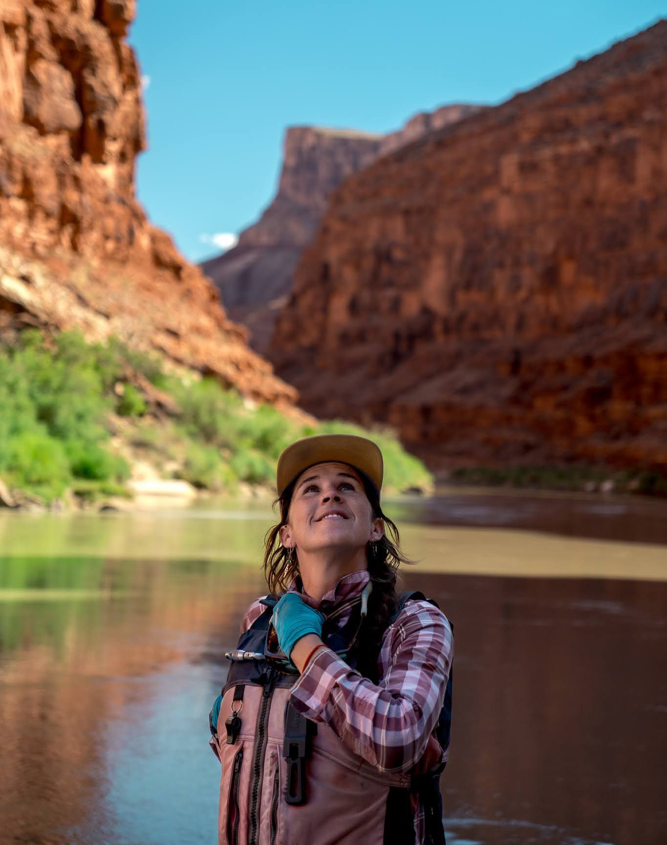 A woman is reading a book while standing next to a river.