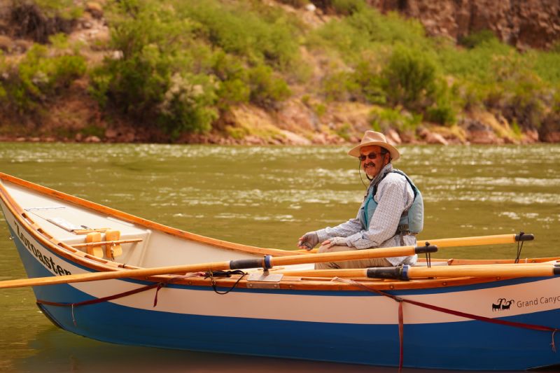 A man is rowing a boat on a river.