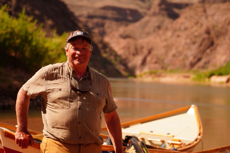 A man is standing next to a boat on a river.