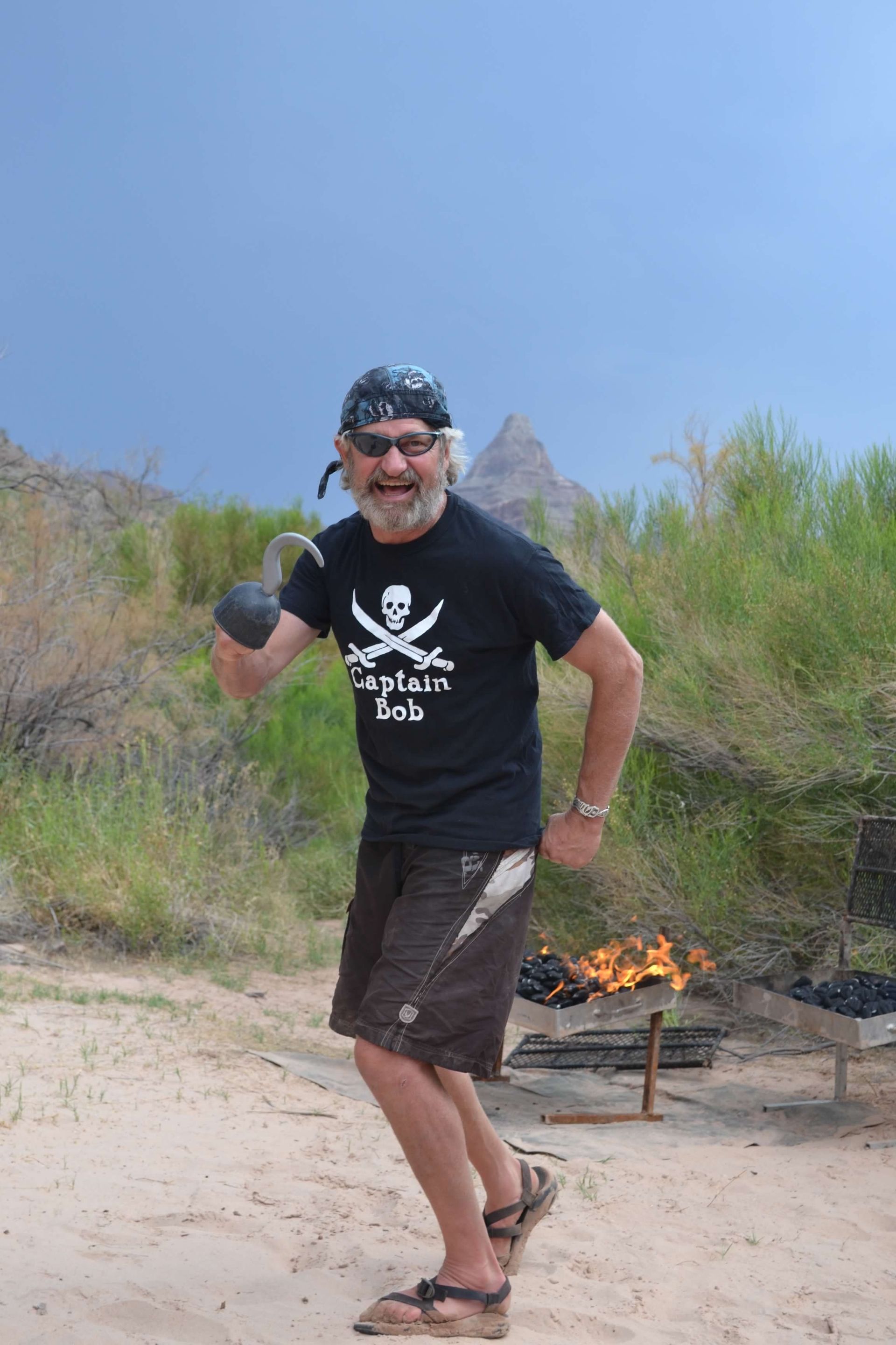 A man wearing a pirate shirt is standing on a sandy beach.
