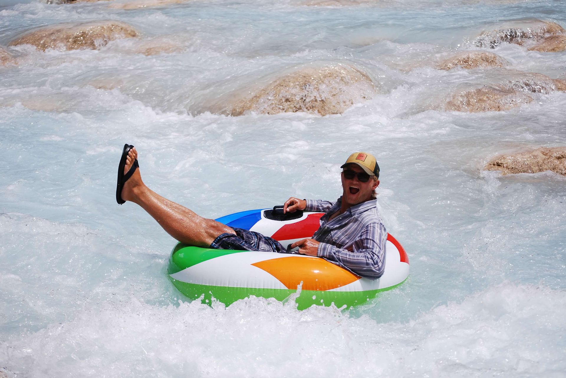 A man with a beard and a blue jacket is standing in front of tents.