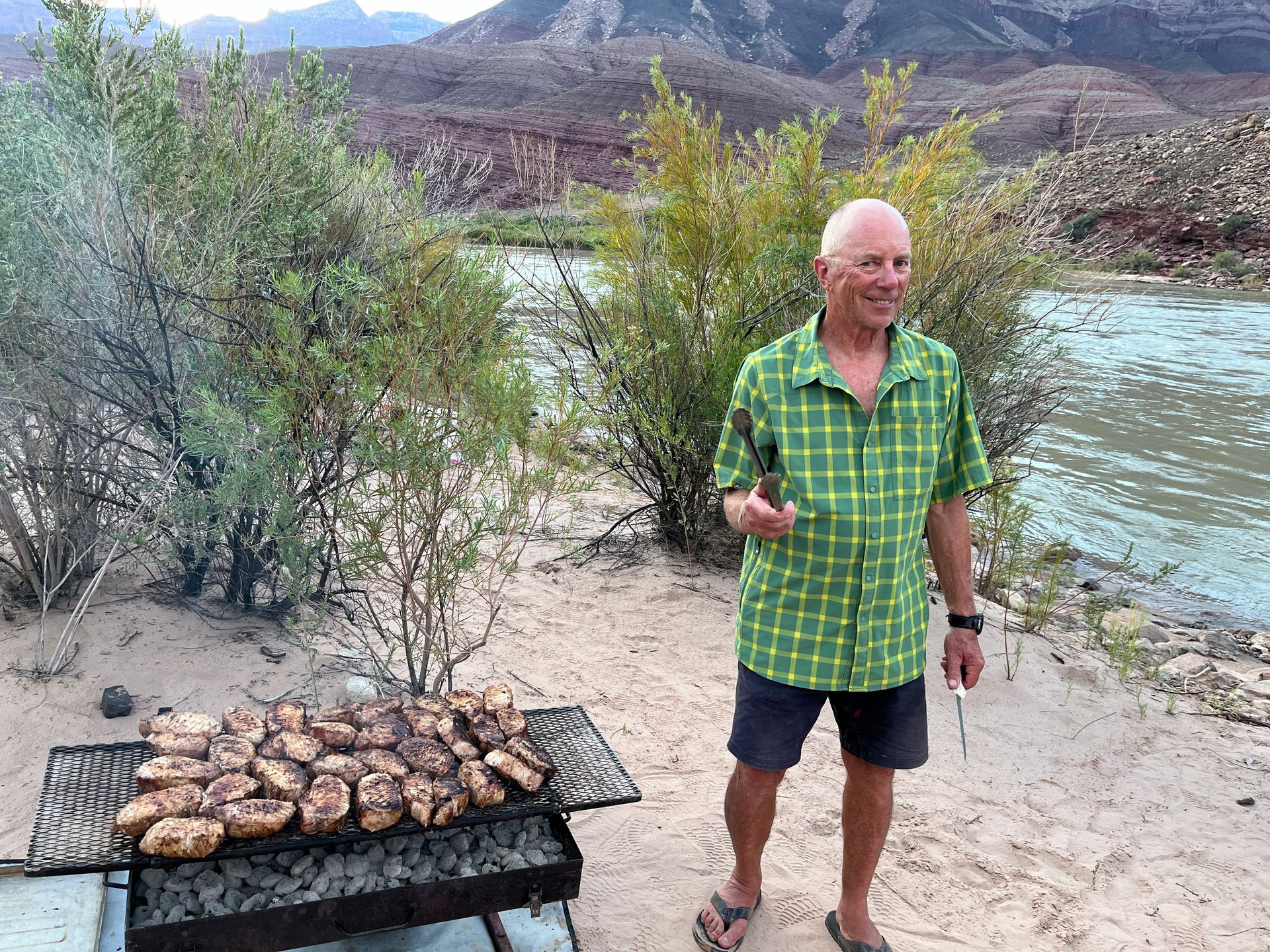A man wearing a life vest is standing in front of a body of water.