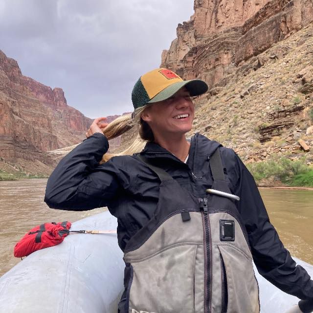 A woman is sitting in a blue raft on a river.