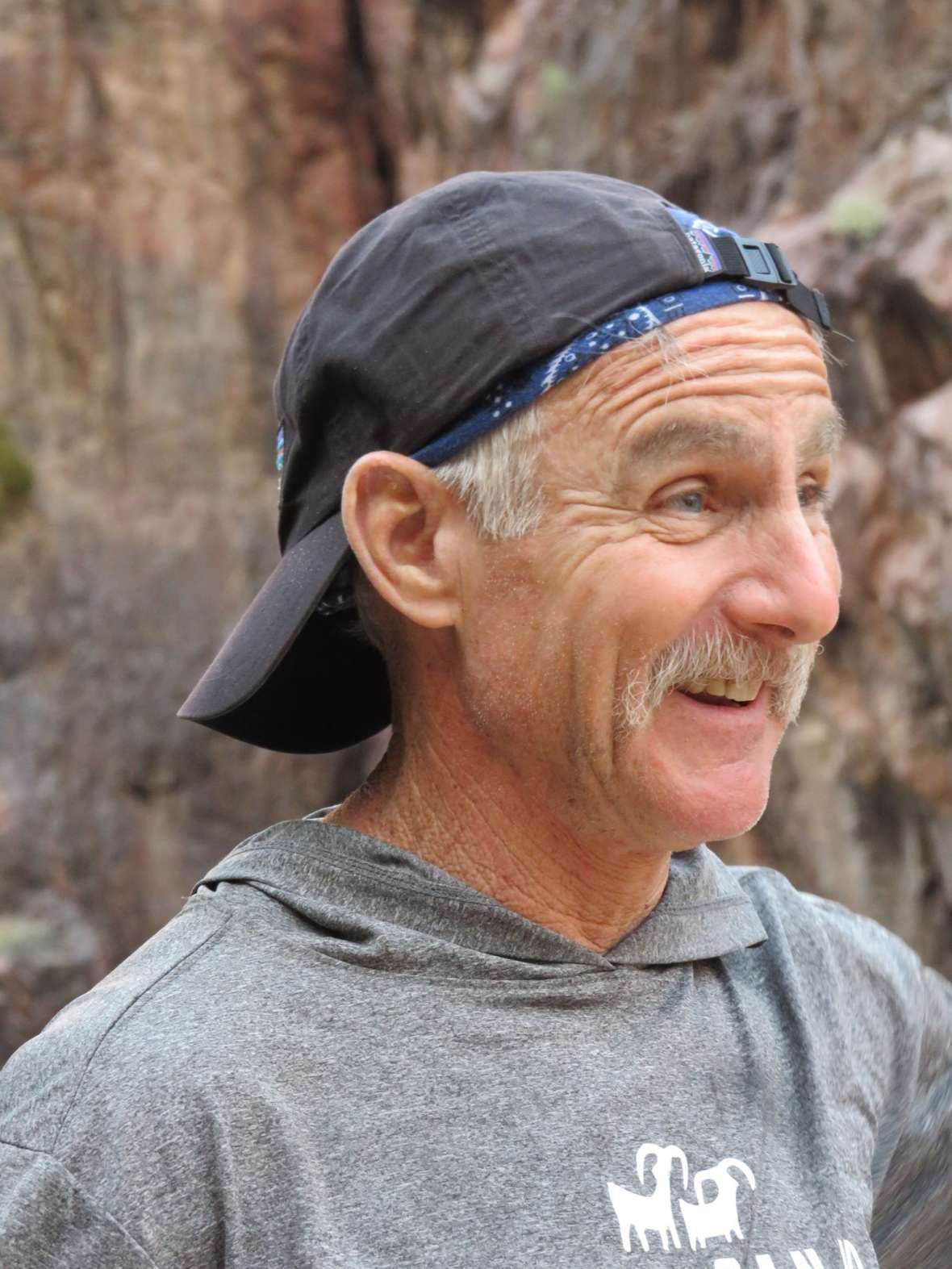 A man with a mustache wearing a hat and a hoodie