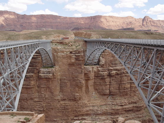 A bridge over a canyon with mountains in the background