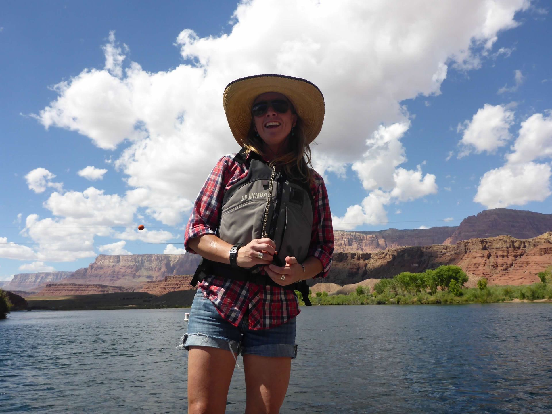 A woman wearing a hat and sunglasses is standing in the water