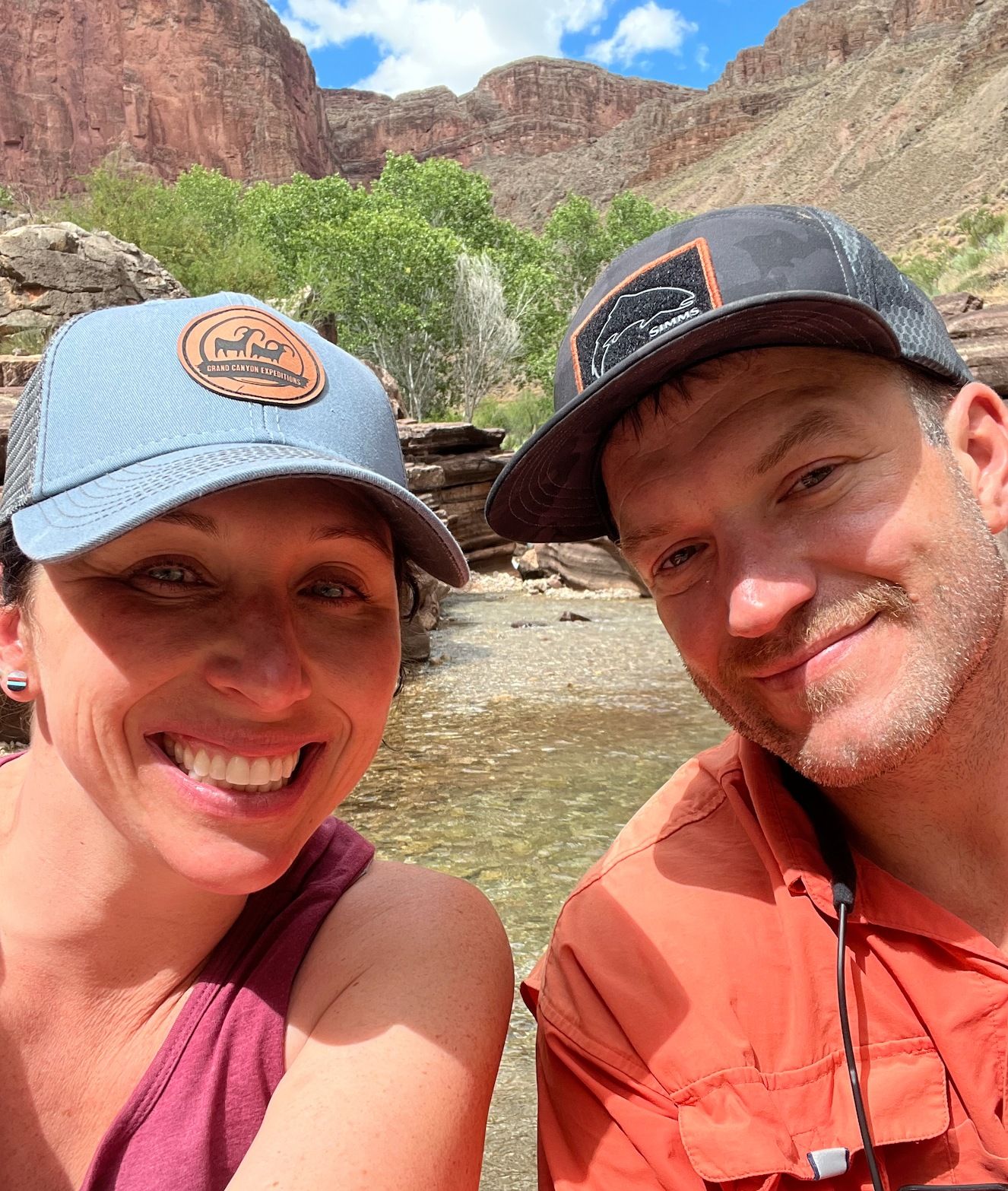 A man and a woman are posing for a picture in front of a river.