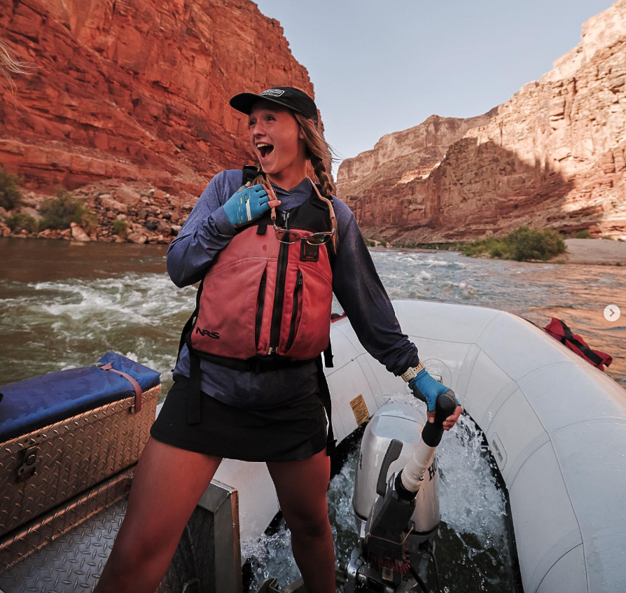 A woman in a life vest is standing on a boat