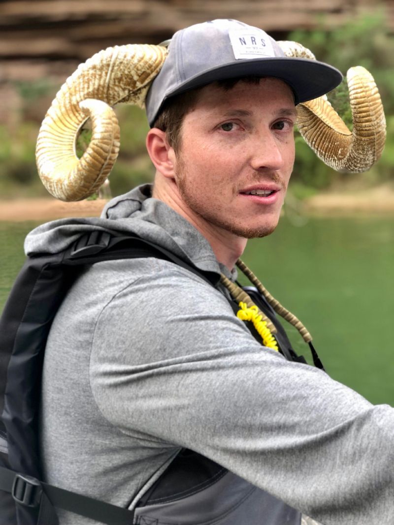 A man wearing a hat with ram horns on it.