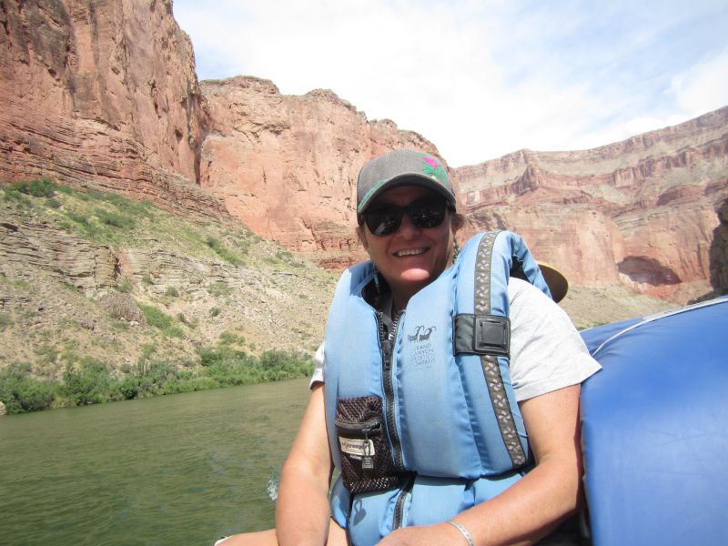 A man wearing a life jacket and sunglasses is sitting on a boat.