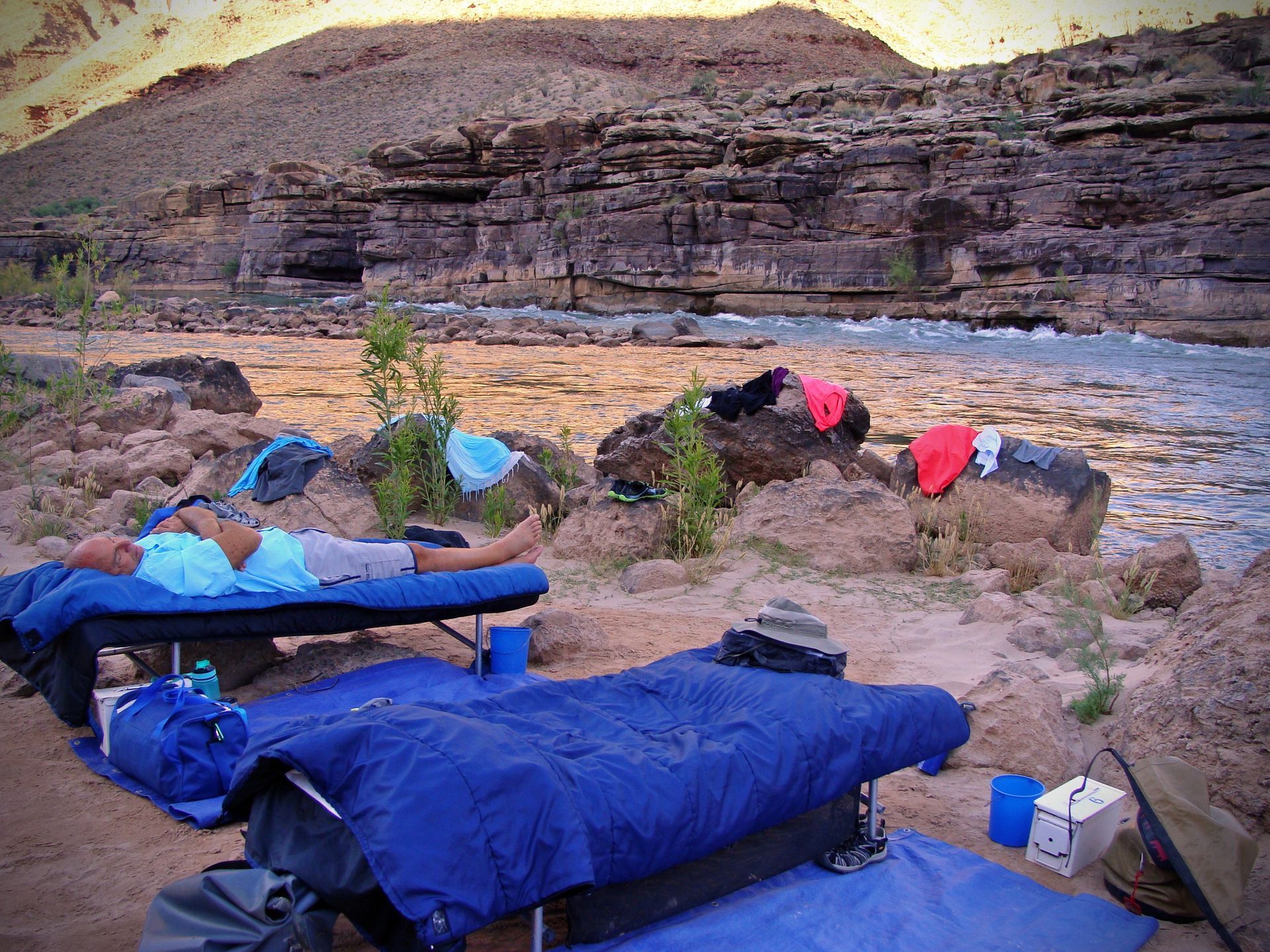 A man is laying on a bed next to a river.