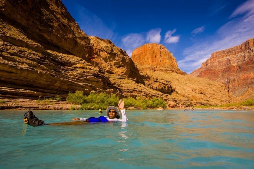A person is floating on their back in a river.