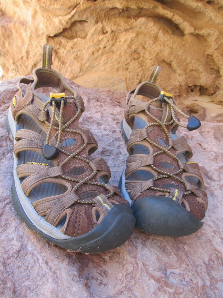A pair of brown sandals are sitting on a rock.