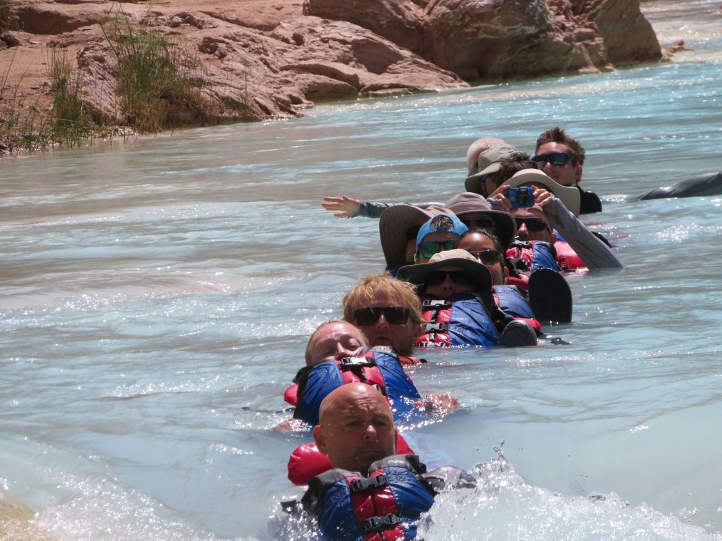 A group of people in life jackets are swimming in a river