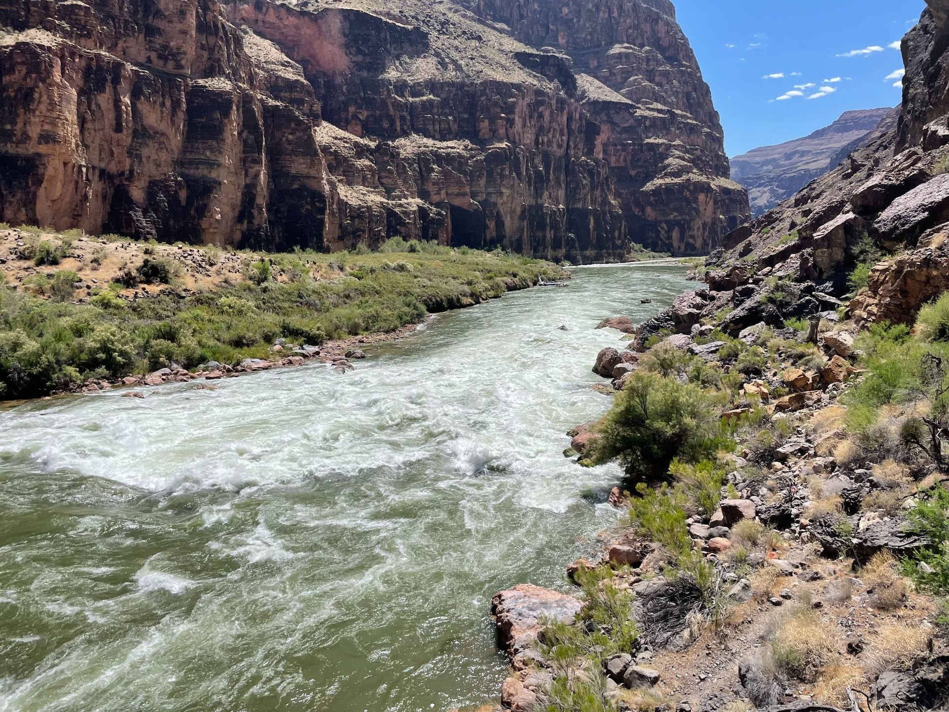 Rushing river flowing through a rocky canyon under a clear blue sky