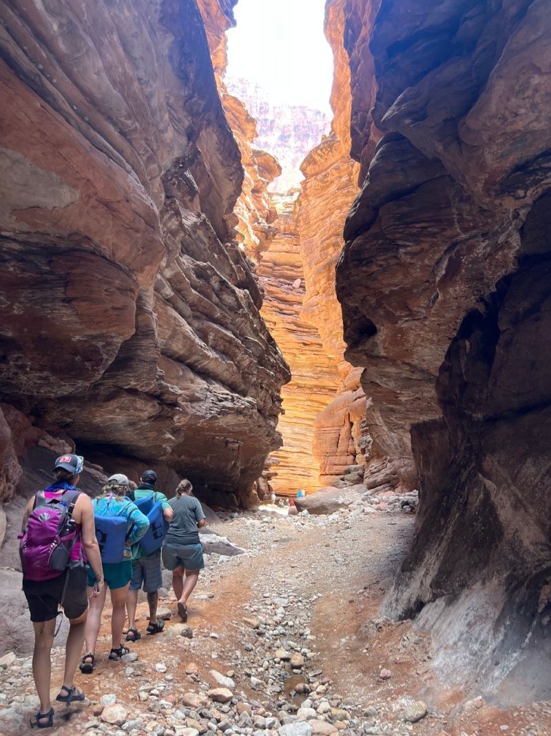 A group of people are walking through a canyon.