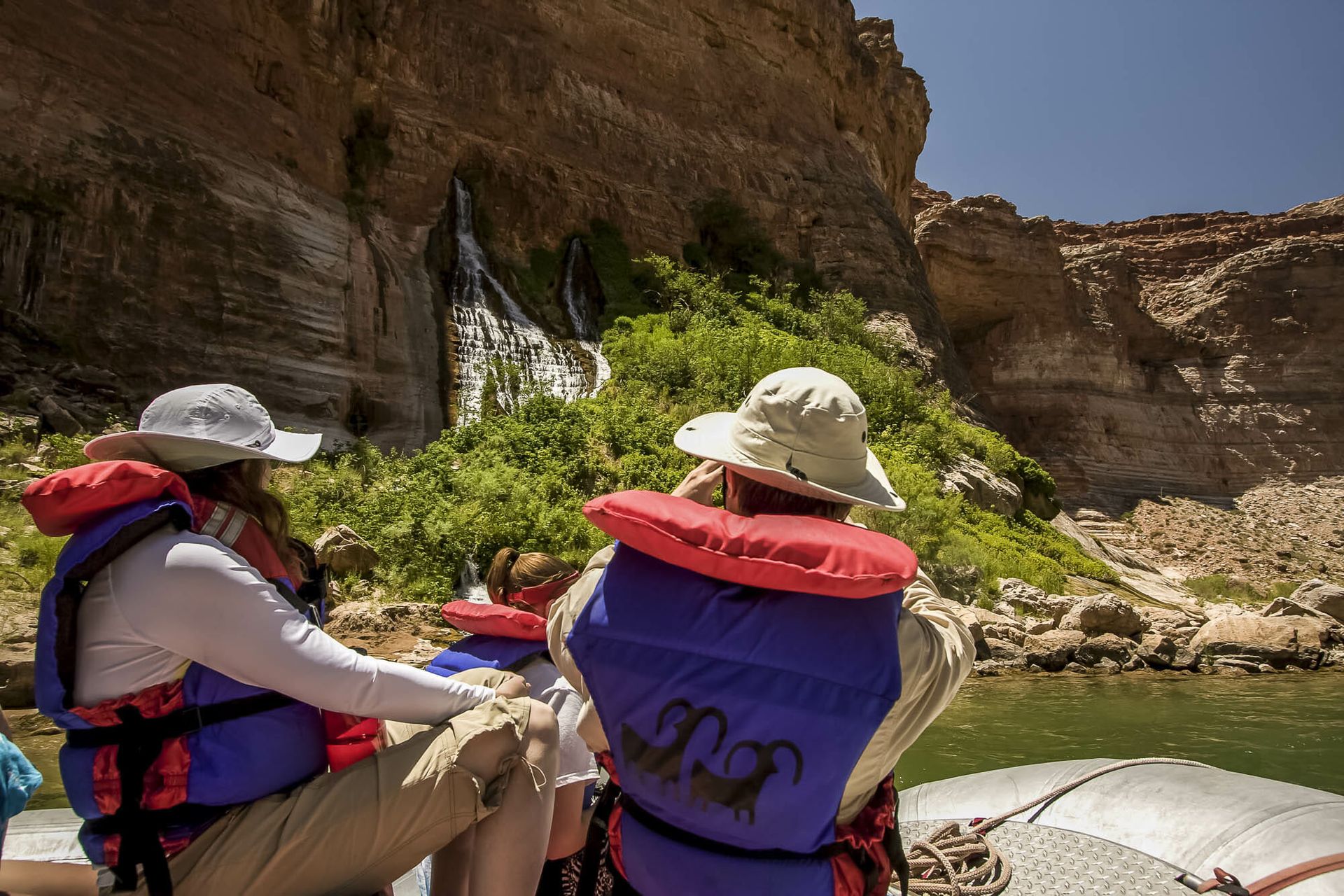 A group of people are sitting on a boat looking at a waterfall.