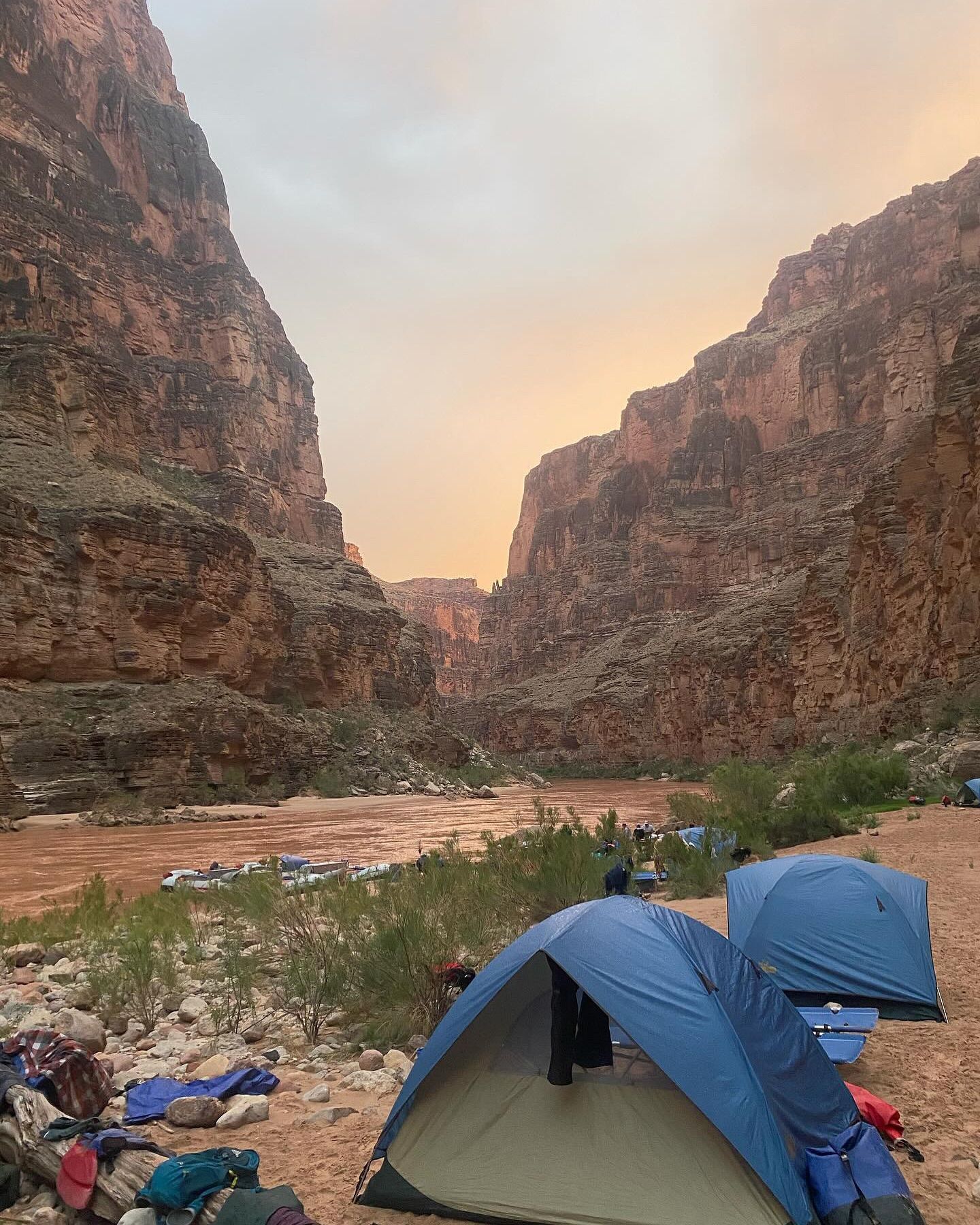 A blue tent is sitting in the middle of a canyon next to a river.