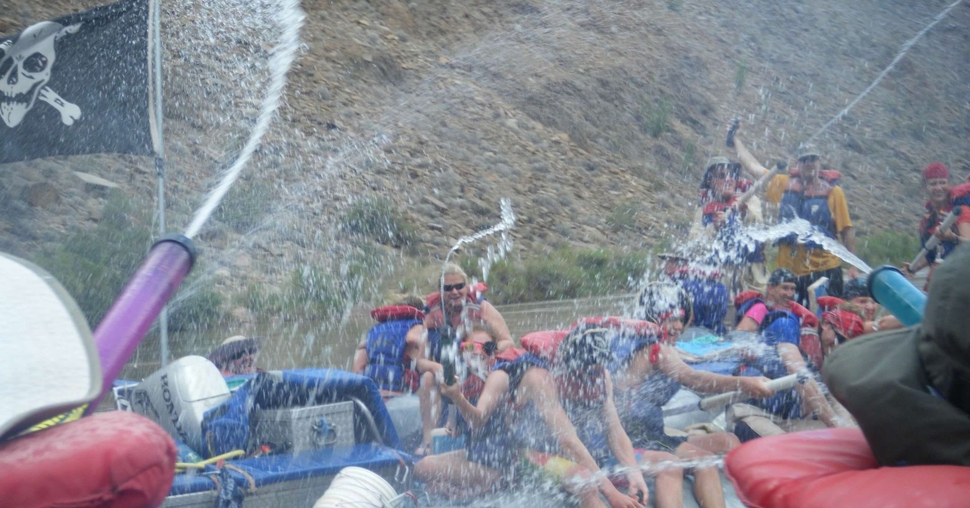 A group of people rafting down a river with a pirate flag in the background