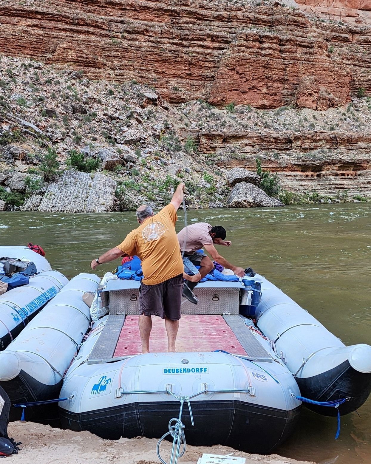 A man in a yellow shirt is standing on a boat that says raft up