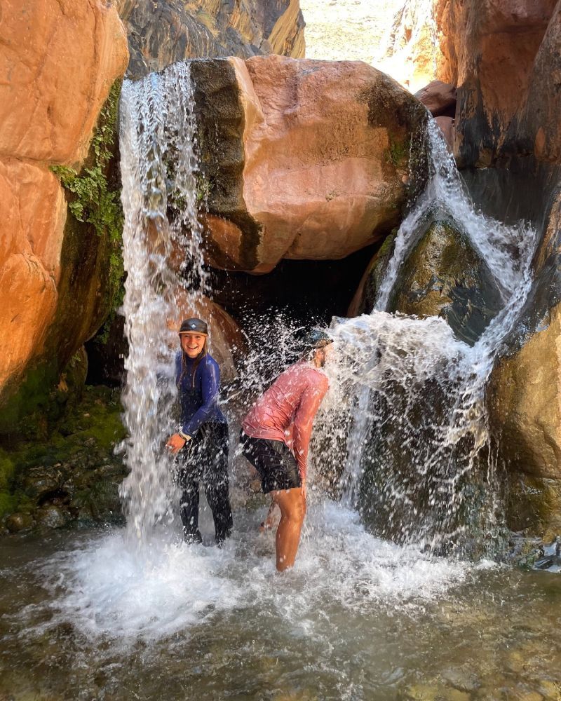 Two people are standing in front of a waterfall