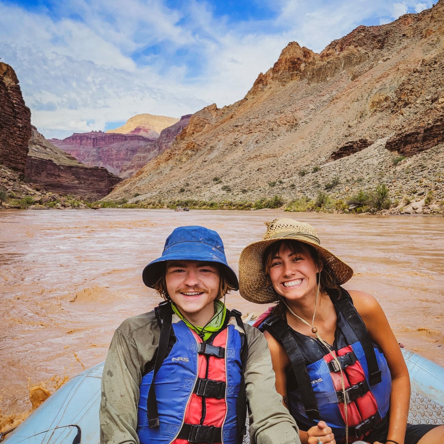 A man and a woman are sitting in a raft on a river.