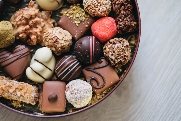 Assorted chocolates and truffles in a round box on a wooden surface