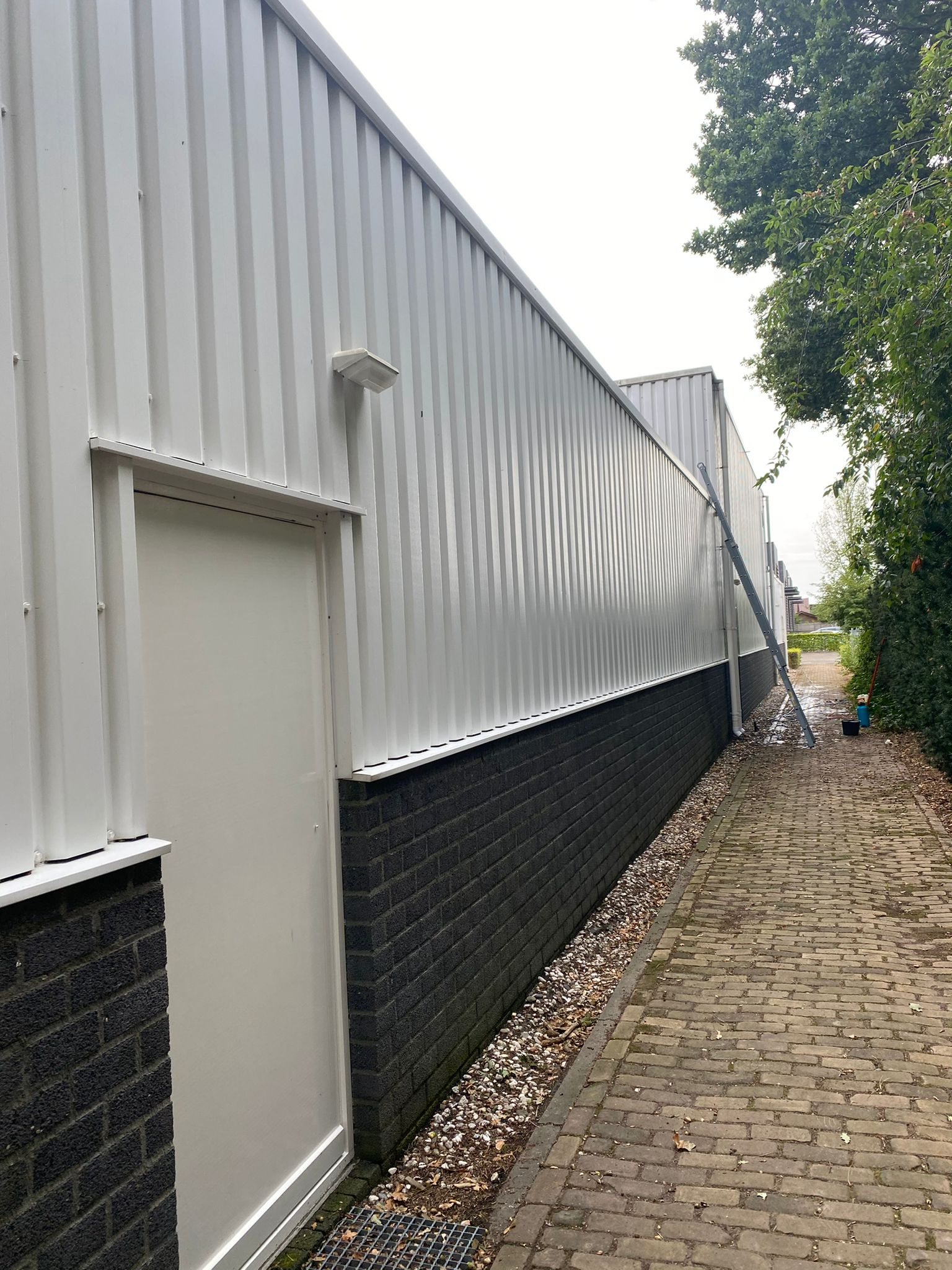 een bakstenen loopbrug met een wit gebouw op de achtergrond