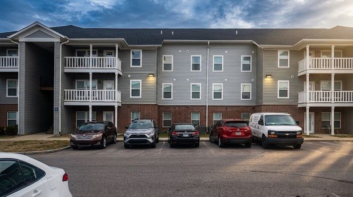 Apartment complex with parked cars in front at dusk