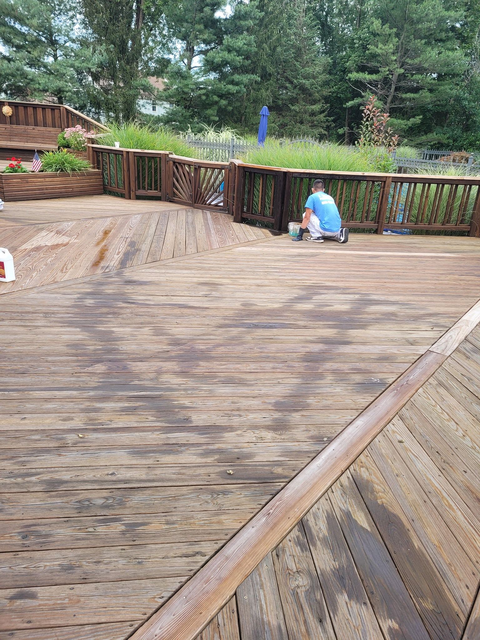 Worker refinishing Home Deck with wood paint.