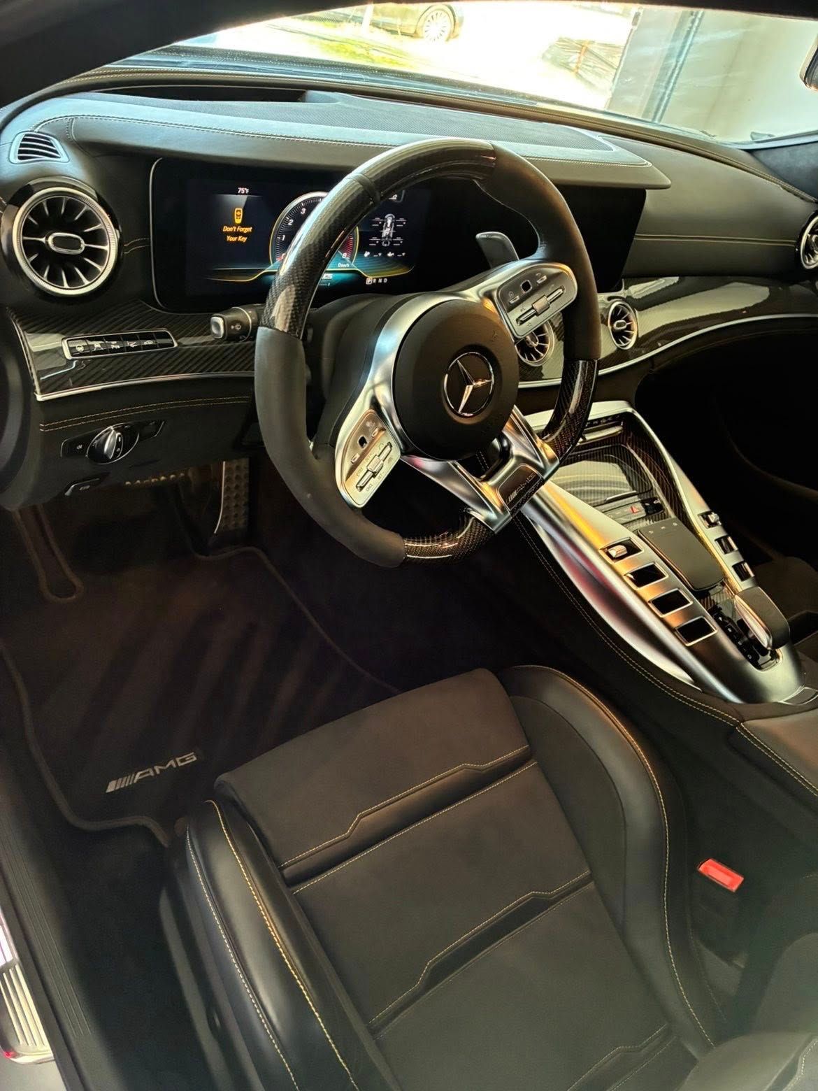 Luxury car interior with black leather seats, steering wheel, dashboard display, and center console.