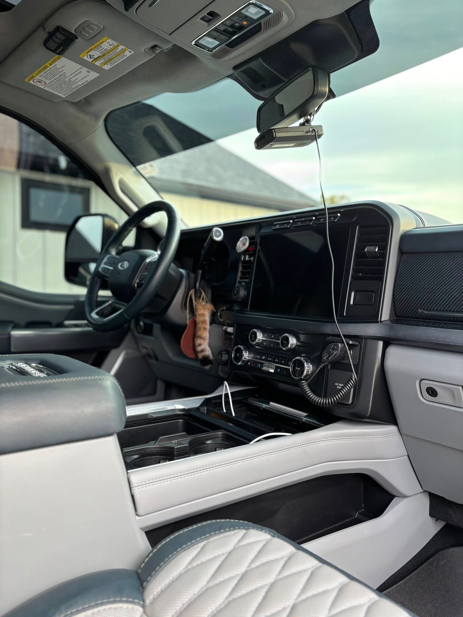 Luxury truck interior with quilted white seats, black dashboard, and steering wheel visible from the driver’s side.
