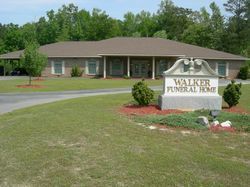Walker Funeral Home building with a sign in front and a landscaped lawn on a sunny day
