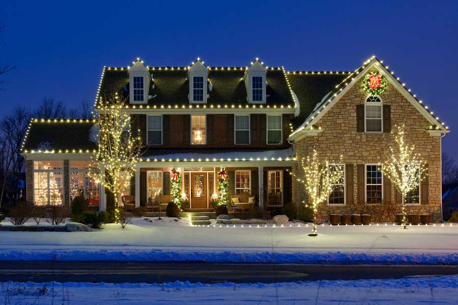 A large brick house is decorated with Christmas lights.