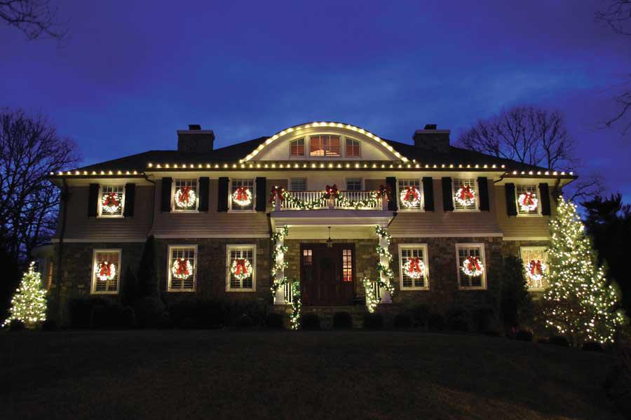 A large house is decorated with Christmas lights and wreaths