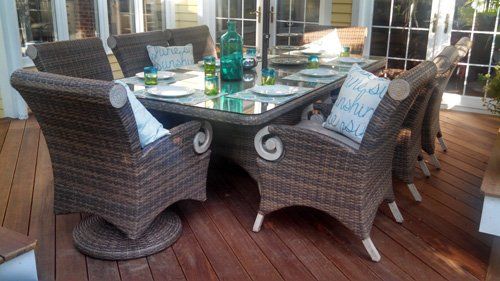 A wicker dining set with a table and chairs on a wooden deck