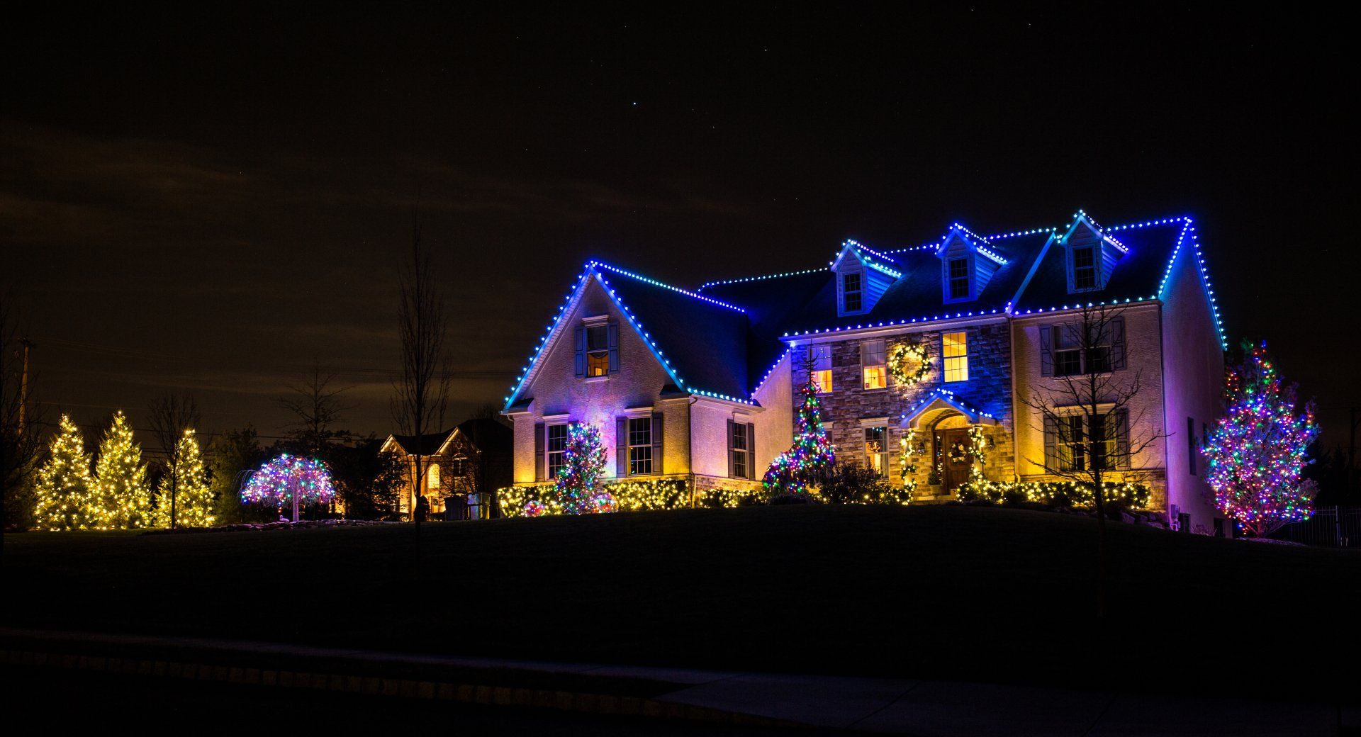 A large house is decorated with christmas lights at night.