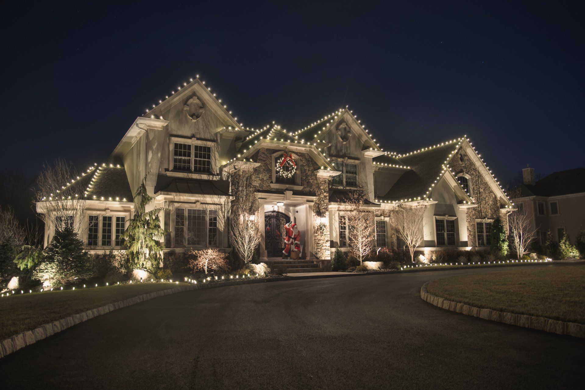 A large house is decorated with Christmas lights at night.