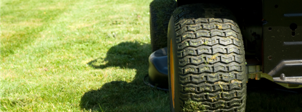 A close up of a lawn mower tire on a lush green lawn.