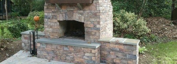 A brick fireplace is sitting on top of a concrete patio.