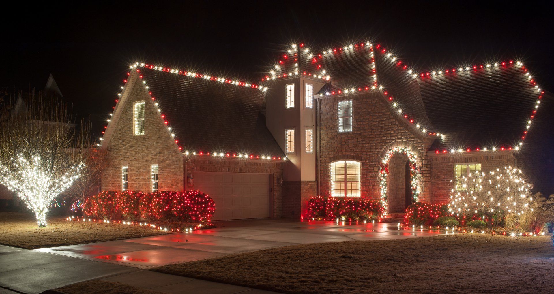 A large house is decorated with christmas lights at night.