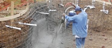 A man is pouring concrete into a pool.