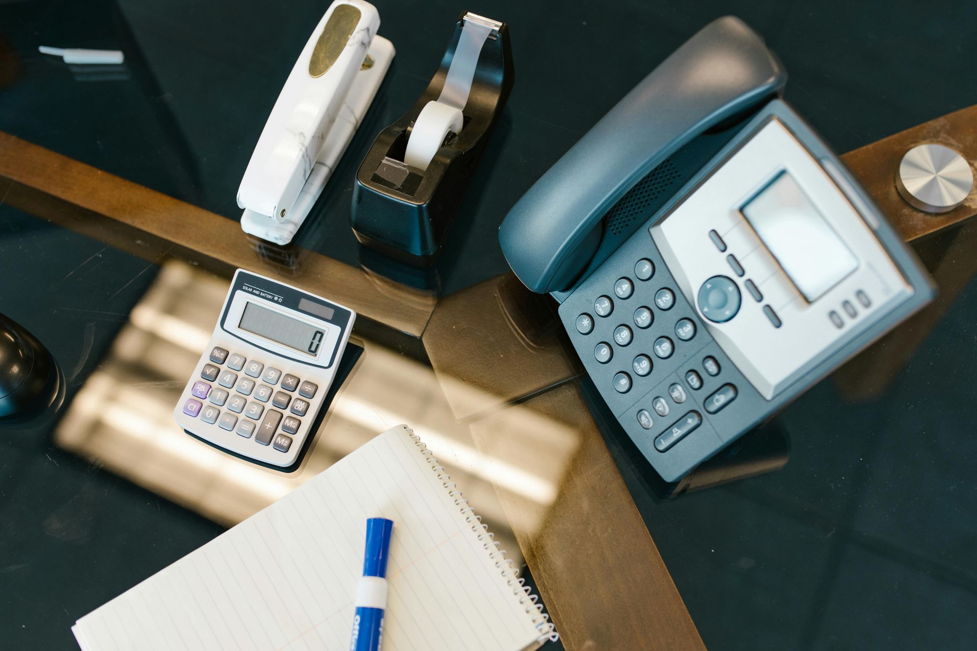 Office desk with calculator, telephone, stapler, and notebook with pen